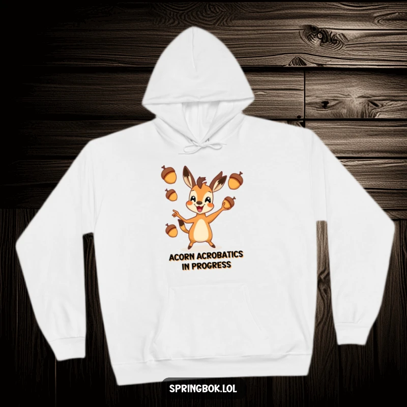 Funny springbok hoodie depicting a happy springbok skillfully juggling three acorns, perfect for cozying up with a laugh.